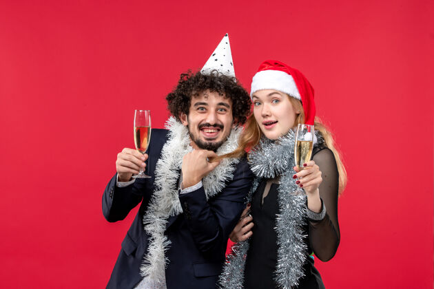年轻夫妇正面图：年轻夫妇在红桌假日圣诞爱情派对上庆祝新年风景服装庆祝