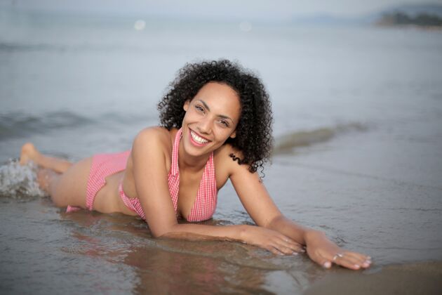 沙滩特写镜头：一位黑发女士穿着泳衣躺在沙滩上海滩放松诱惑