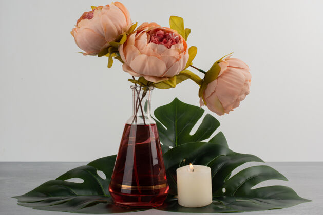 植物粉红色的玫瑰花在玻璃花瓶和蜡烛里花瓶玫瑰蜡烛