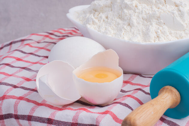 鸡蛋碎鸡蛋 擀面杖和一碗面粉放在桌布上料理碎大头针