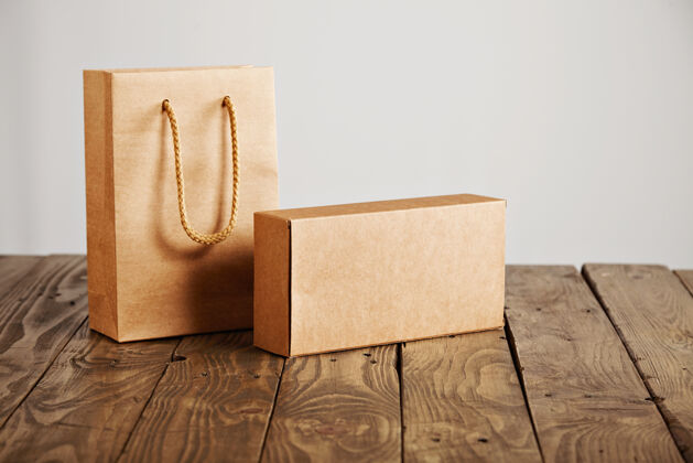 木材工艺纸袋和纸板空白盒呈现在质朴的木桌上 隔离在白色背景上包裹包装搬运