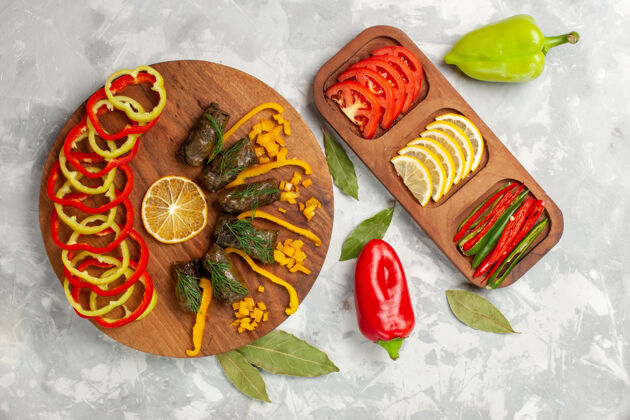 晚餐俯视图在浅白的桌子上放着切好的甜椒和美味的蔬菜盘子肉容器