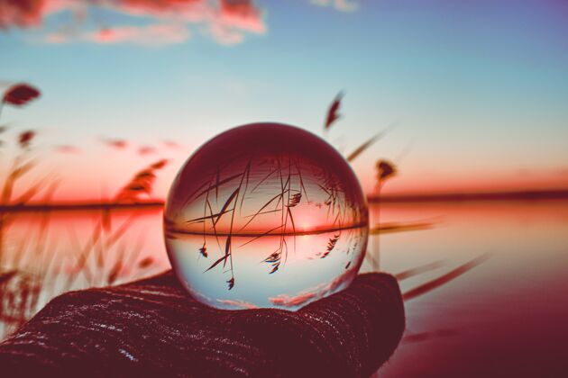 翻转创造性的水晶镜头球与周围高大的绿色湖泊摄影阳光颜色反射