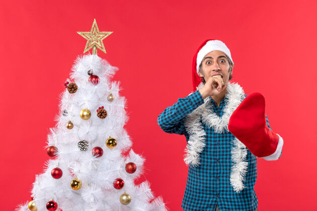衬衫一个戴着圣诞老人帽子 穿着蓝色条纹衬衫 穿着圣诞袜子的年轻人大吃一惊袜子礼物圣诞树