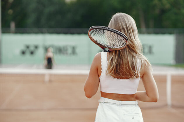 健身穿着t恤的快乐的年轻女子拿着网球拍和球的女子嬉戏活动人