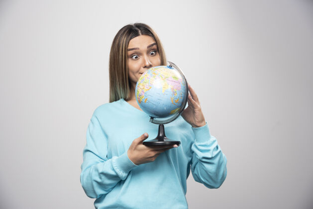 地理穿着蓝色运动衫的金发女孩拿着一个地球仪 猜测地点 玩得很开心人地球教育