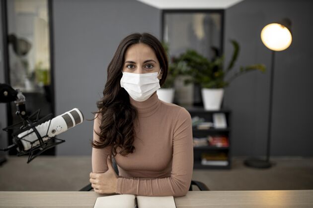 电信一个戴着医用面罩的女人在广播室的正视图医疗面具传输公告