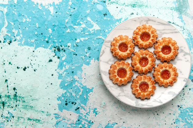 顶部俯视美味饼干圆形与果酱形成的浅蓝色背景饼干甜甜饼干面团蛋糕烤披萨灯光饼干