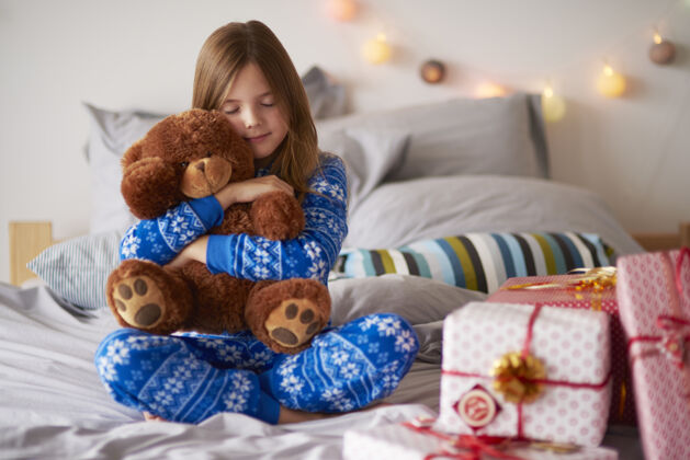 泰迪熊小女孩在圣诞节拥抱泰迪熊床做梦圣诞礼物