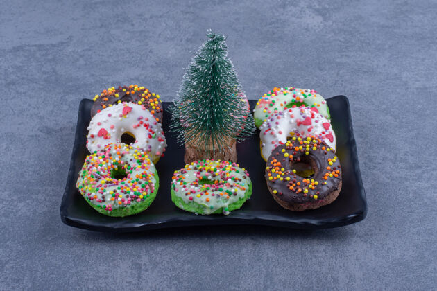 洒一个黑色的盘子里有美味的甜甜圈和小圣诞树深色好吃圣诞节