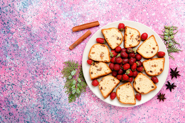 生的顶视图蛋糕片与新鲜的红色草莓在粉红色的桌子蛋糕烤甜饼干颜色派糖饼干曲奇视图盘子