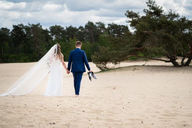花束一对新人在婚礼当天走在沙滩上的风景照团聚已婚心