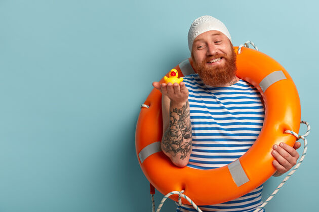 救生圈快乐友好的红发男人抱着橡皮黄小鸭 在炎热的夏天喜欢在海里游泳欧洲红发大笑