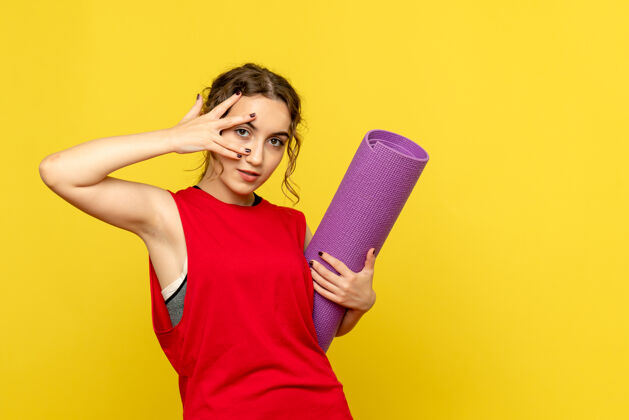 运动装年轻女子与黄色墙壁上的紫色地毯合影的正面视图年轻女性年轻人