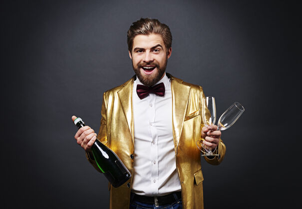 新开朗的男人拿着一瓶香槟和香槟笛庆祝迪斯科舞活动