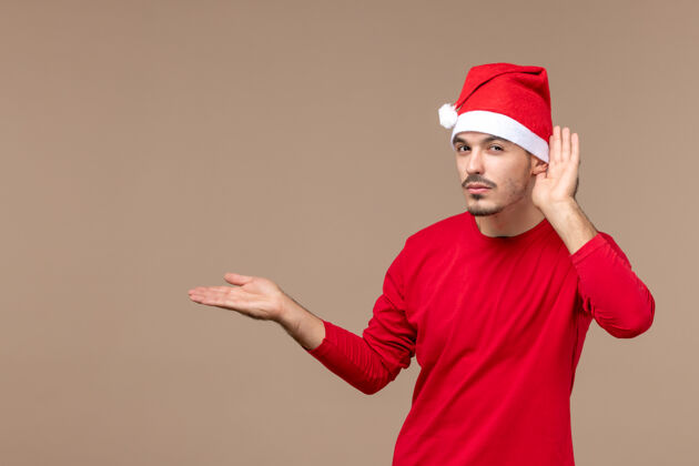 一正面图年轻男性在棕色办公桌上仔细聆听圣诞节情感假期肖像圣诞节成人