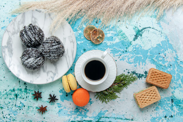 纸巾俯瞰一杯咖啡 配上法式马卡龙华夫饼和巧克力蛋糕 蓝色表面蛋糕烘焙饼干甜巧克力糖色蛋糕华夫饼纸