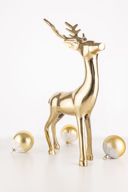 美丽垂直拍摄的金色鹿雕像与圣诞装饰球隔离在一个白色的背景鹿垂直纪念品