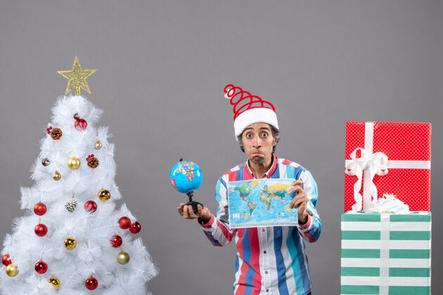 举行前视图惊讶的男子与螺旋弹簧圣诞帽举行世界地图和地球仪惊喜的人圣诞老人旅行