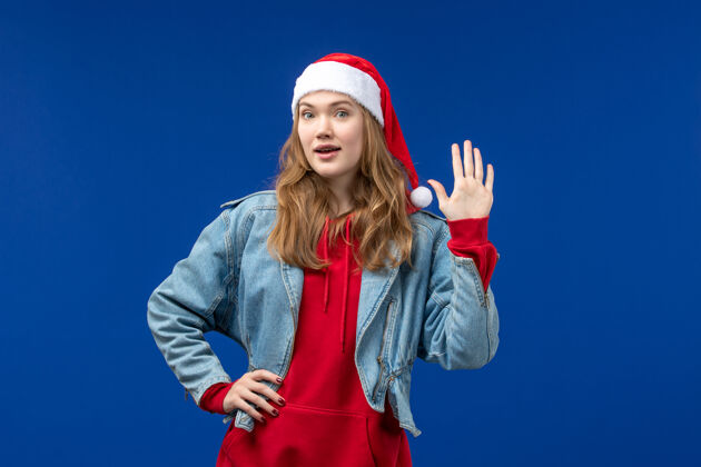 微笑前视图年轻女性 戴着淡蓝色背景的红色圣诞帽 感受着圣诞节的色彩帽子可爱风景
