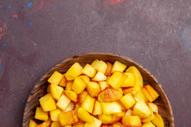 蔬菜俯视图在黑暗的桌子上棕色盘子里切熟的土豆土豆植物芒果