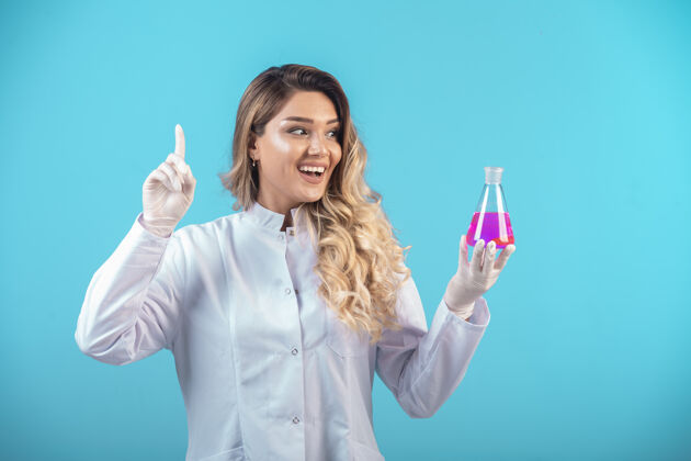 护理穿着白色制服的护士拿着一个装有粉红色液体的化学瓶 想出了一个主意疾病成功临床
