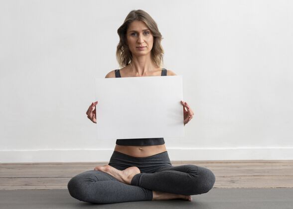 瑜伽在家做瑜伽的女人 手里拿着空白的标语牌练习锻炼反省