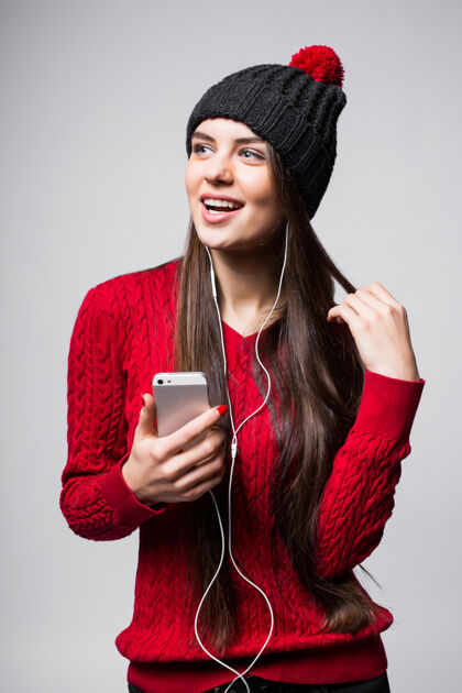 电话可爱的年轻女子用耳机欣赏音乐的肖像 隔着白墙音乐舞蹈积极