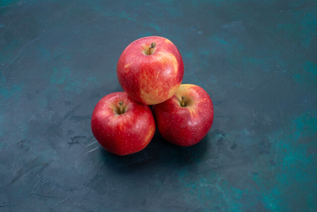 食用前视新鲜的红苹果醇香 新鲜的水果放在深蓝色的书桌上 水果新鲜醇香 成熟的树新鲜可食用的饮食