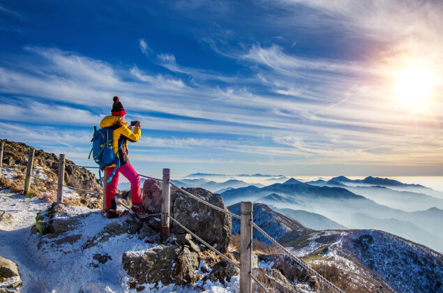 峰会冬天 年轻的徒步旅行者在山顶用智能手机拍照健康采取顶端