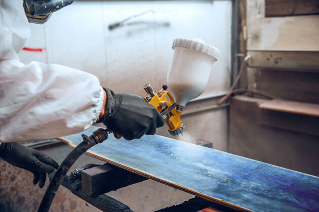 车间一家工厂的油漆-用喷枪对木头进行工业油漆木工喷涂木材
