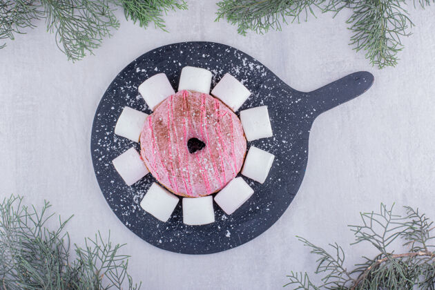 美味柏树在白色背景的木板上绕着一圈棉花糖和一个甜甜圈美味甜点糕点
