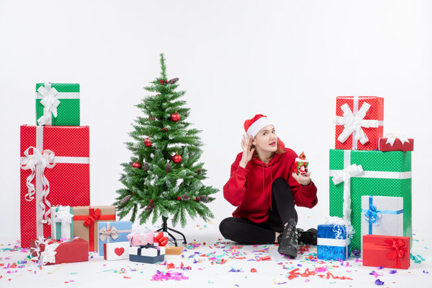 节日前视图年轻女子围坐在一个白色的墙上拿着礼物冬青情感圣诞
