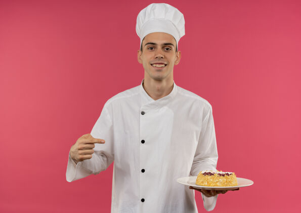分面带微笑的年轻男厨师穿着厨师制服 拿着蛋糕点在盘子上 并留有复印空间拿着男制服