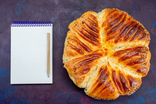 记事本顶视图美味的糕点烤面包形成糕点与记事本在黑暗的背景橘子食物柑橘