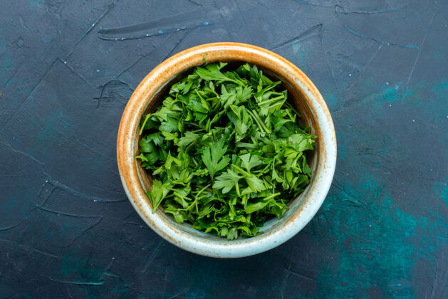 药草在深蓝色桌子上的圆锅里俯瞰新鲜的绿色食物碗深蓝色