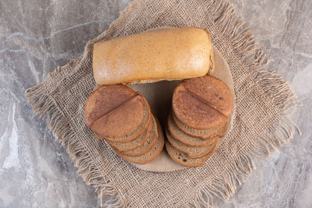 顶部整条面包放在大理石板上的棕色切片面包后面顶部视图面包面粉
