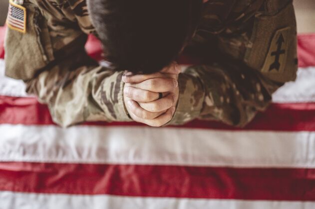 祈祷美国士兵在他面前举着美国国旗哀悼和祈祷希望爱国者士兵