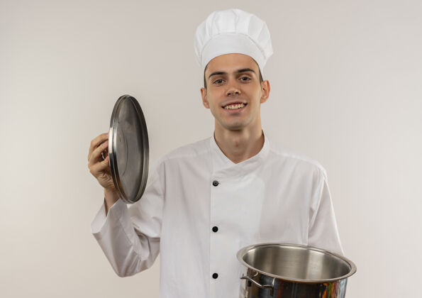 戴着面带微笑的年轻男厨师穿着厨师制服拿着平底锅和锅盖男制服厨师