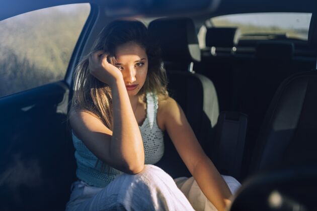 心烦意乱一个美丽的年轻白人女性在一个领域的汽车前排座位摆姿势的水平镜头凉爽悲伤汽车