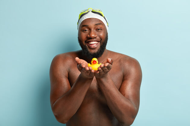 运动员相貌亲切体贴的黑皮肤爸爸把橡皮玩具小鸭送给孩子 在沙滩上度过时光 在海里游泳运动胡子水平