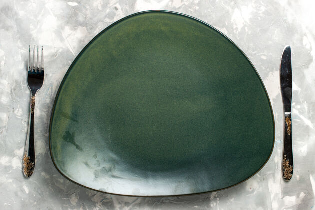 餐具顶视图：浅灰色桌子上的绿色空盘子与刀叉隔离烹饪托盘叉子