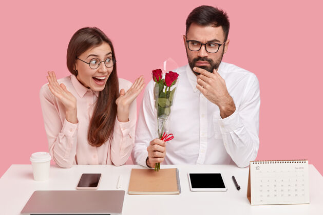笔记本电脑办公室关系概念严肃的男主管给秘书送花 感受爱情 在工作场所约会 和电子设备坐在一起女人收到玫瑰高兴工作区团队