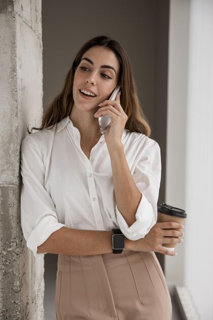 女士微笑的女商人一边喝咖啡一边打电话企业家咖啡垂直