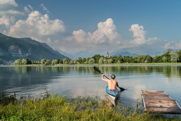 划船一个人划船在树木和群山环绕的湖面上的美丽镜头山湖白天