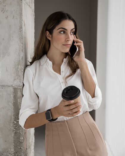 女士女商人一边喝咖啡一边打电话的前视图企业家垂直经理