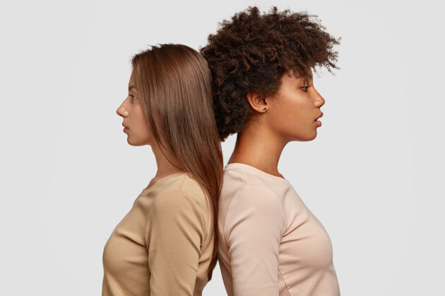 多种族两个混血女人站在侧面背对着对方 有着若有所思的表情 穿着休闲装团结外观卷发