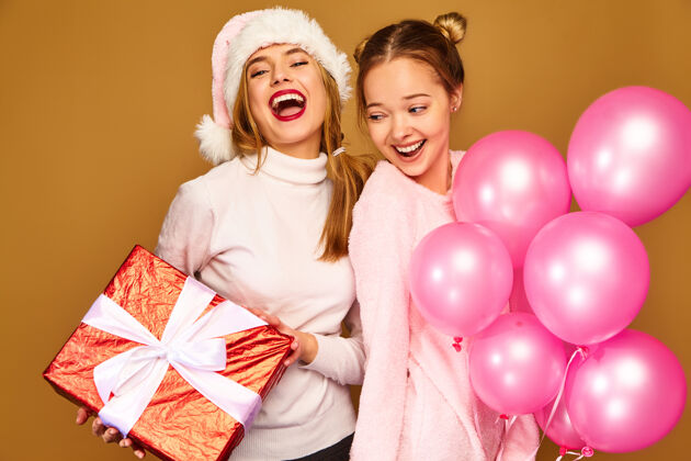 帽子圣诞节带着大礼盒和粉色气球的模特们人们年轻聚会