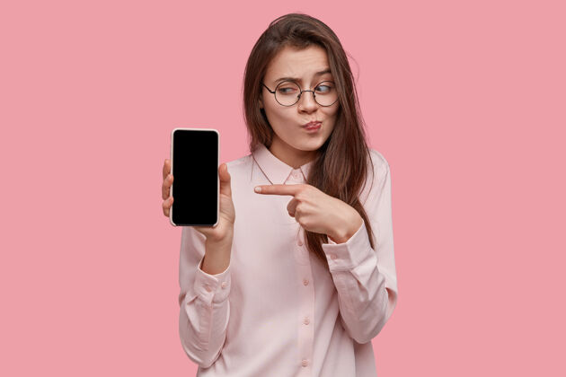Indexfinger迷人的黑发女性镜头将现代手机和模拟屏幕放在手边 为她最喜欢的公司的新产品做广告女士女性通讯