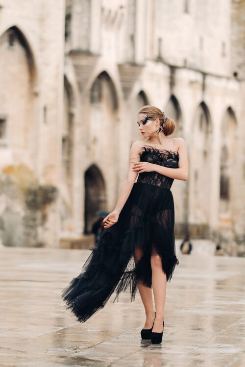 老城区一位身着黑色婚纱的时尚新娘在法国古城阿维尼翁摆出姿势穿着漂亮的黑色连衣裙的模特在普罗旺斯拍照配件运动黑裙